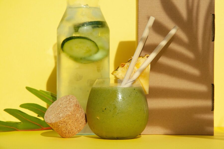 Delicious green smoothie with pineapple and cucumber water against a yellow backdrop. Perfect summer refreshment.