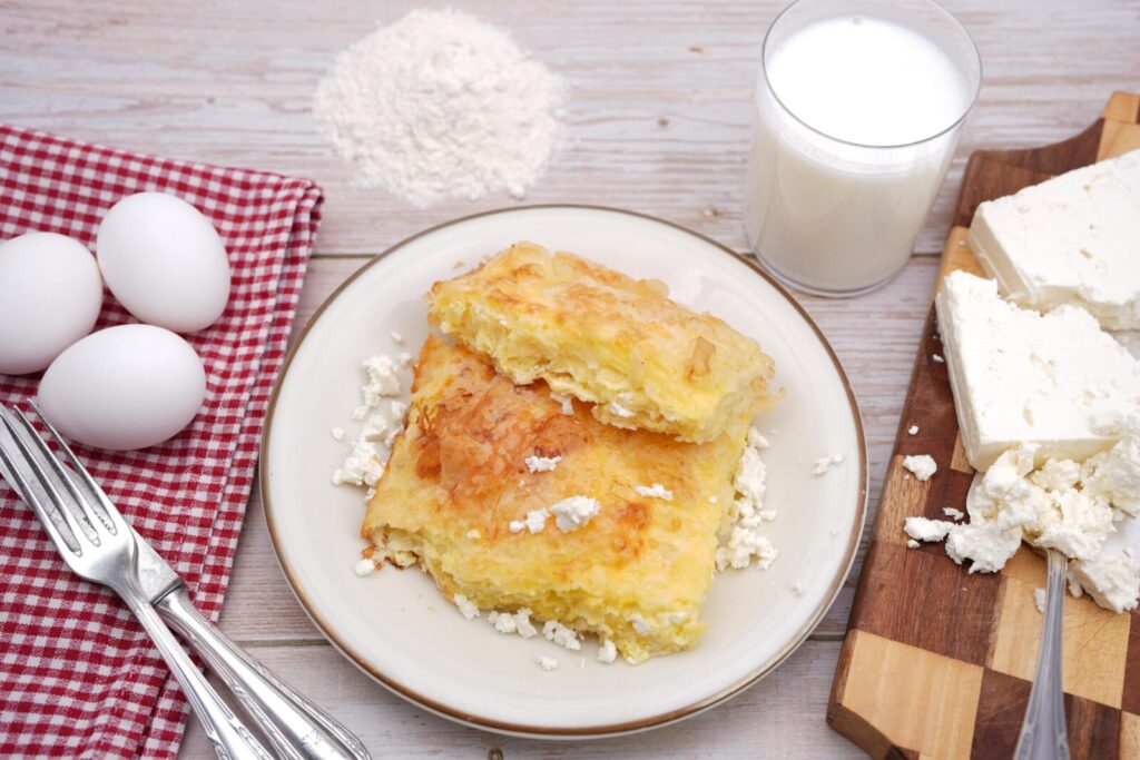 Scrumptious homemade pastry served with cottage cheese, eggs, and milk on a wooden table.