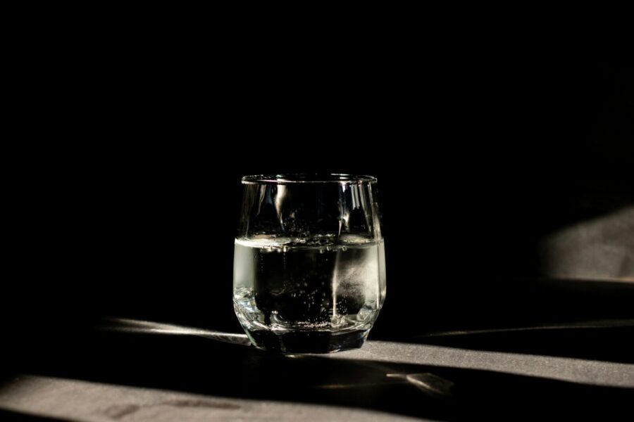 A glass of carbonated water illuminated in a moody dark environment, perfect for refreshment themes.