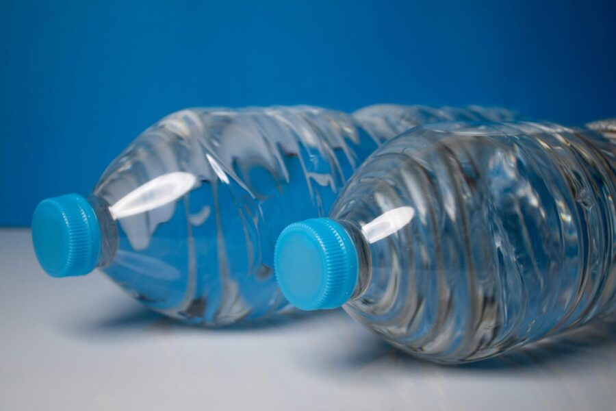 Close-up of clear plastic water bottles with blue caps on a blue background.