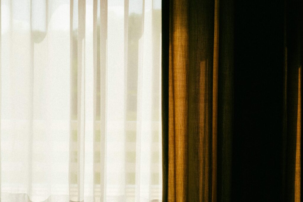 Light filters through sheer and opaque curtains, creating a warm, dreamy ambiance.