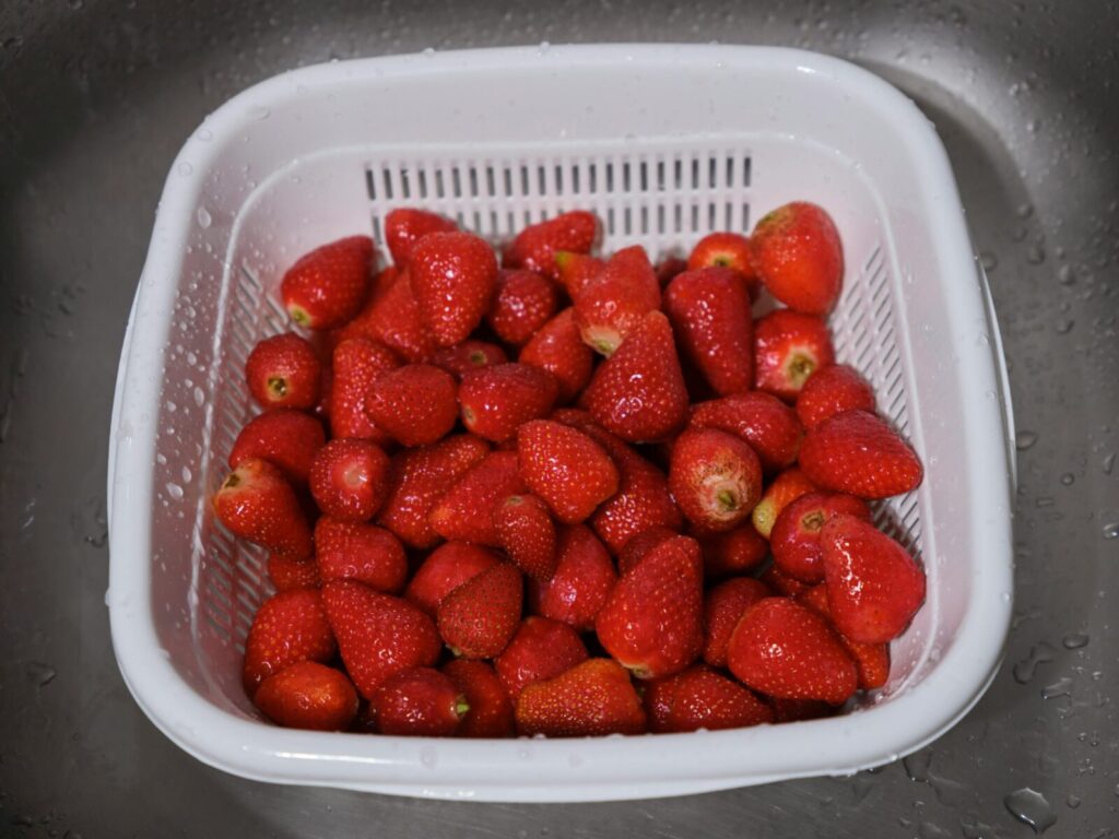 A close-up of fresh strawberries in a white plastic colander. Perfect for healthy eating concepts.