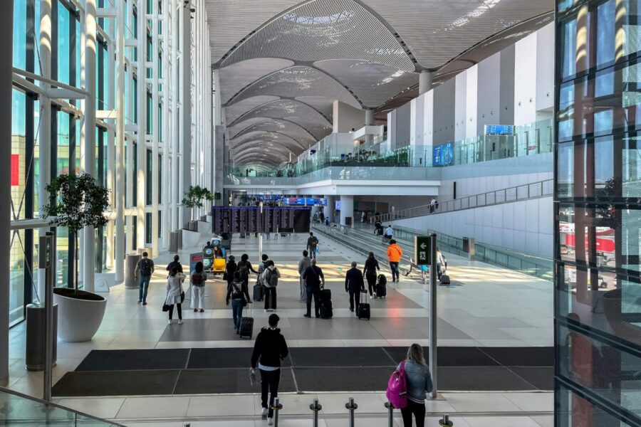 Travelers walking through the spacious modern terminal at Istanbul Airport.