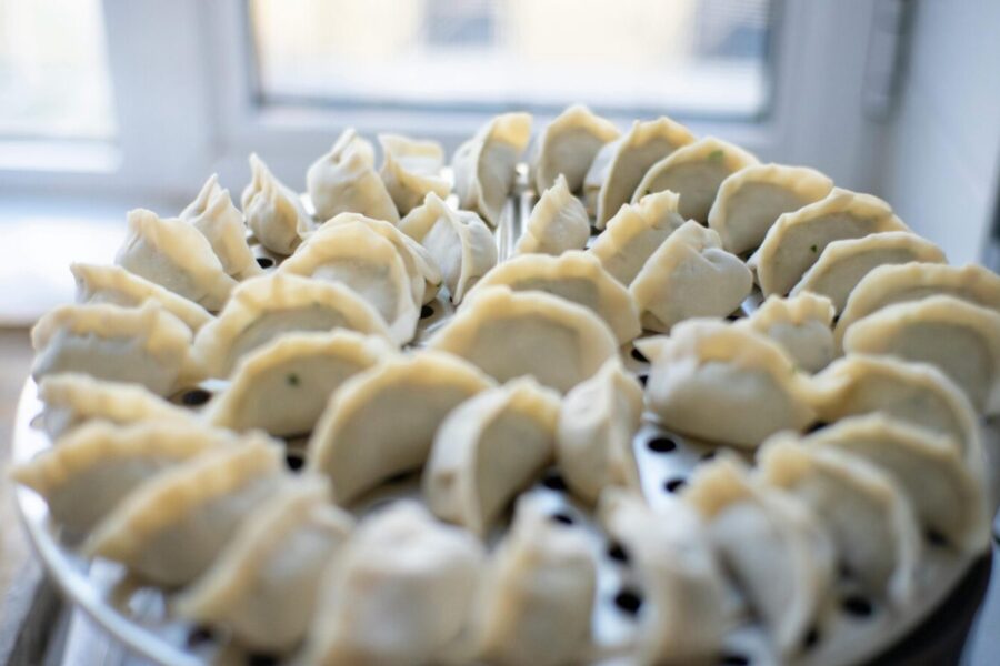 A close-up view of freshly prepared dumplings arranged neatly in a steaming tray near a window.