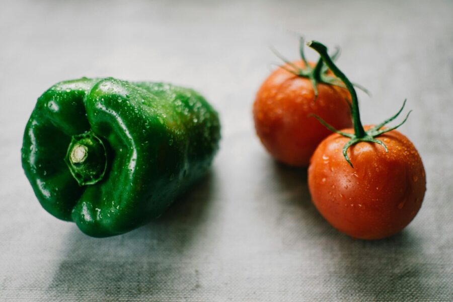 Fresh green bell pepper and tomatoes with water droplets, symbolizing organic farming.