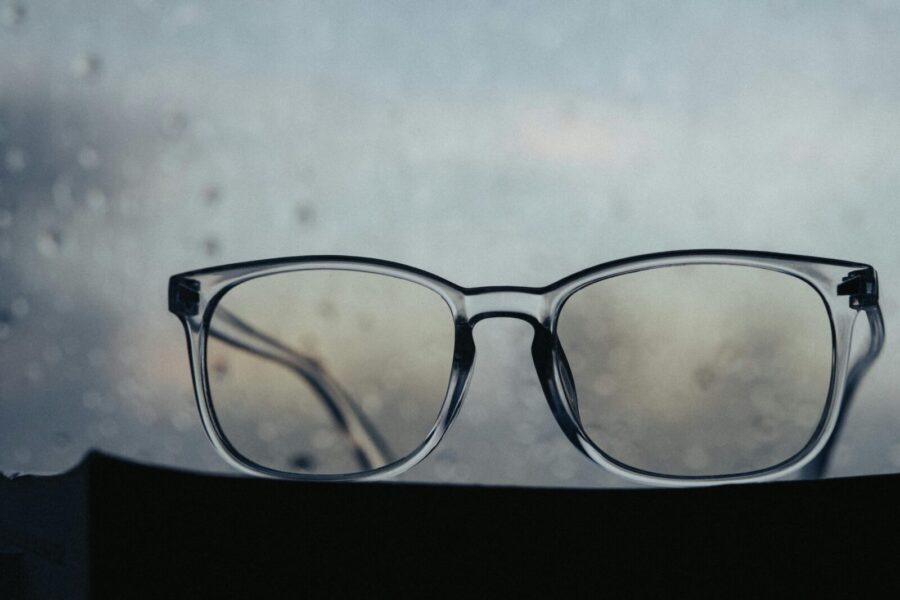 Minimalist close-up of glasses with a raindrop background, creating a serene atmosphere.