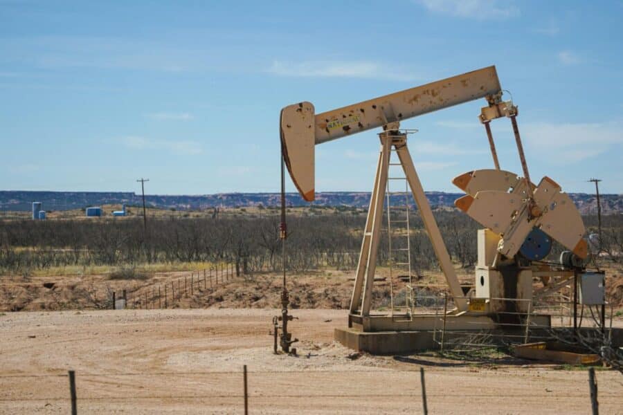 Industrial oil pumpjack in a desert setting under a clear blue sky, illustrating oil extraction technology.