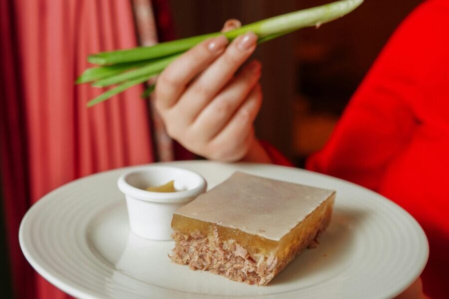 Close-up of a plate with meat jelly and chives, showcasing a fusion of traditional flavors.