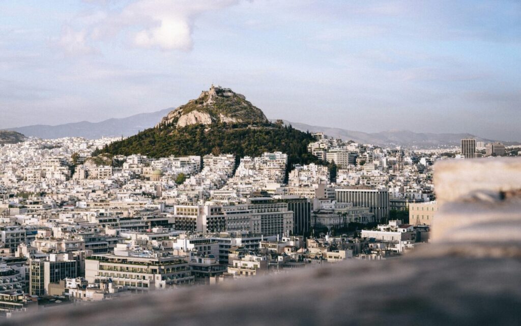Explore the stunning cityscape of Athens with Mount Lycabettus at its center, captured beautifully in this aerial shot.