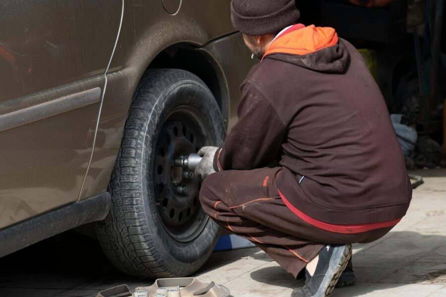 A mechanic working on a car tire, changing it in an auto repair shop.
