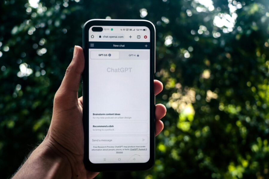 A person uses ChatGPT on a smartphone outdoors, showcasing technology in daily life.