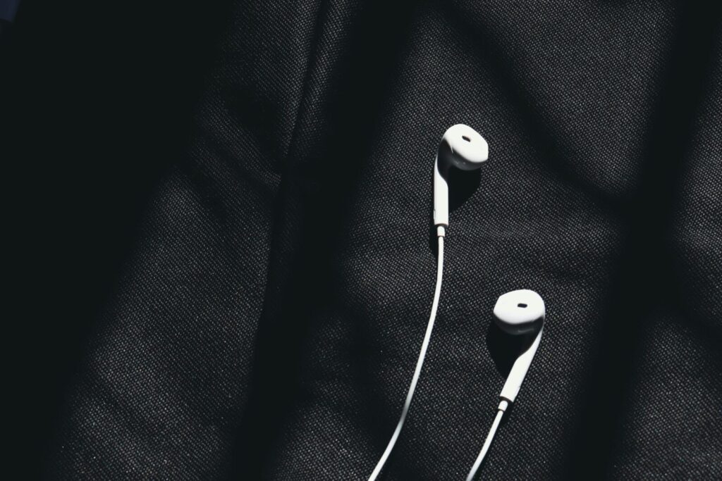 Close-up of white wired earphones on dark fabric creating a minimalist aesthetic.