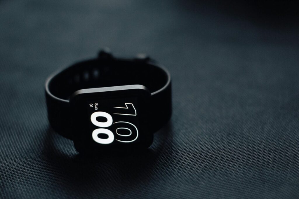 Modern smartwatch displaying time on a sleek dark gray surface, perfect for tech enthusiasts.