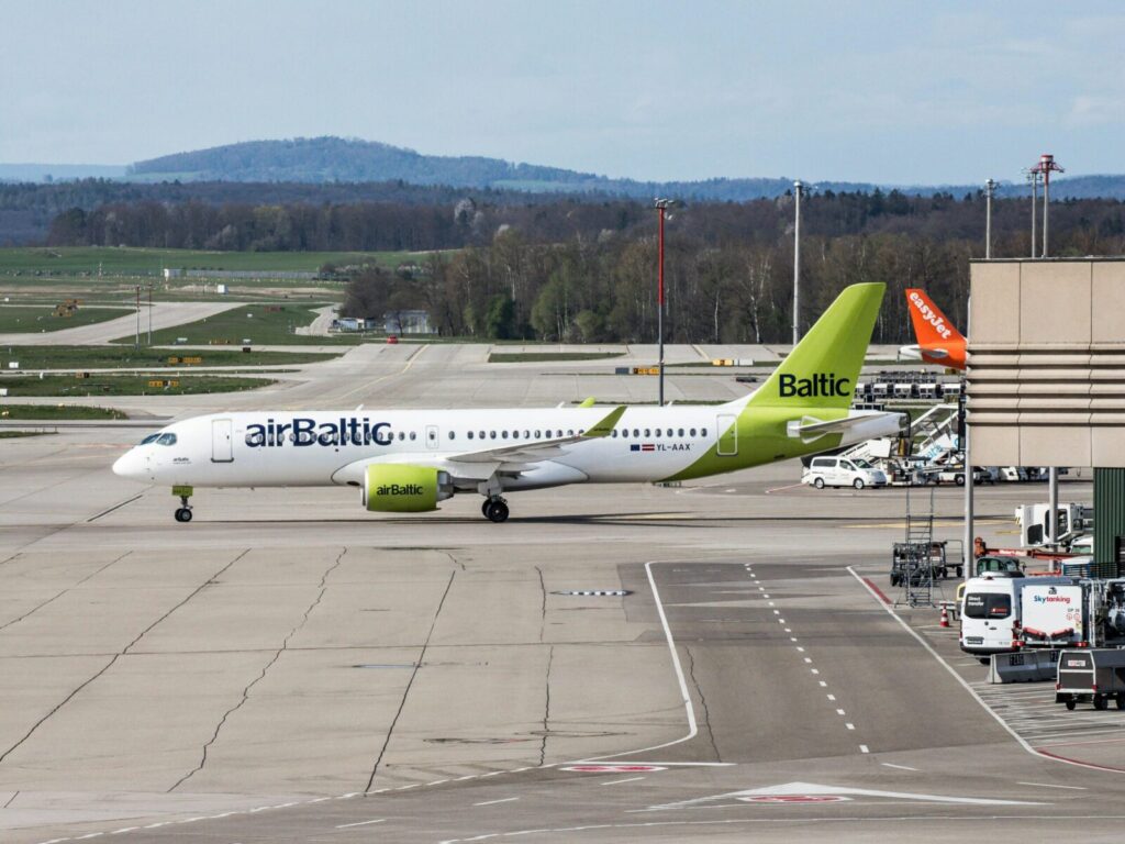 AirBaltic plane taxiing on Zurich Airport runway with distant hills.