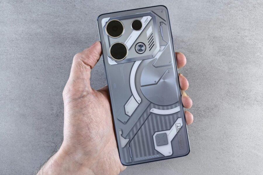 Close-up of a hand holding a futuristic smartphone with a unique back panel design over a gray background.