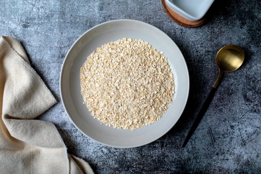 Top view of oats in a bowl with a spoon and linen cloth, perfect for healthy diet themes.