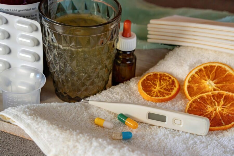 A flat lay of home remedies for cold and flu, featuring herbs and pharmaceuticals.