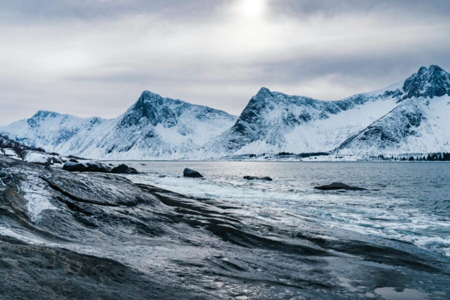 Breathtaking view of snow-covered mountains and icy ocean waters in Norway.