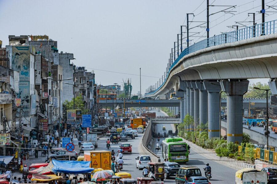Busy street scene in Delhi with elevated metro and urban traffic capturing vibrant city life.