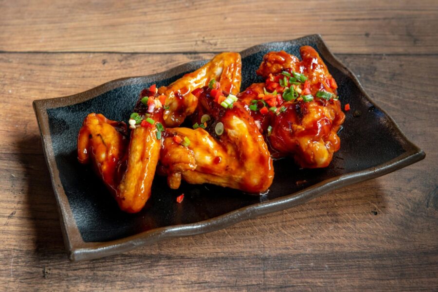 Delicious glazed chicken wings served on a black plate, perfect for appetizers.