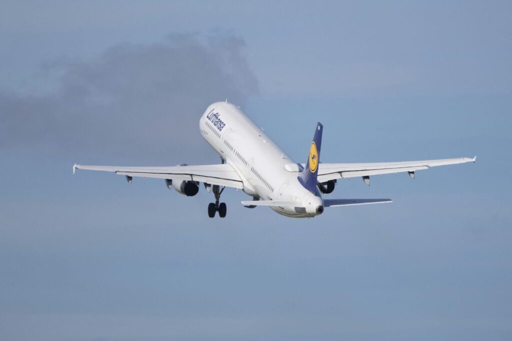 A Lufthansa Airbus A320 aircraft taking off into the clear blue sky.