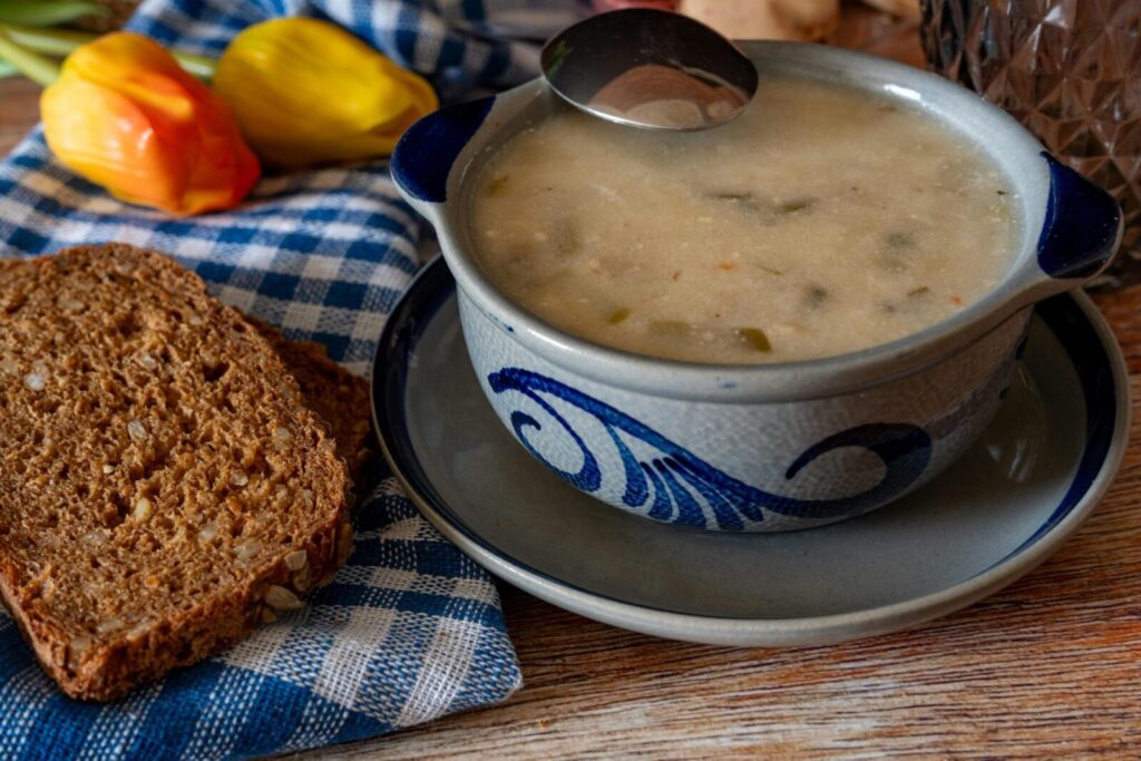 Delicious homemade vegetable soup served with wholegrain bread on a rustic table setting.