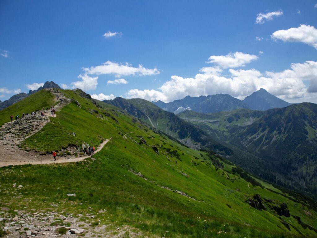 Explore breathtaking views on a hiking trail in Poland's Tatra Mountains under a clear blue sky.