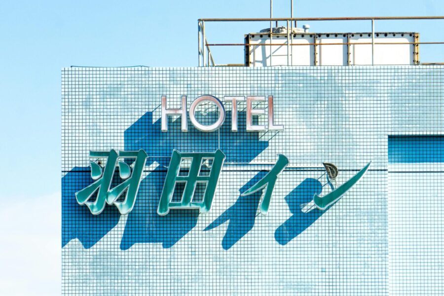 Brightly lit hotel sign with blue tiles under a clear sky, showcasing modern architecture.