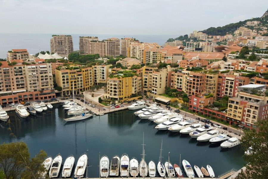 High-angle view of Monaco's marina featuring luxury yachts and colorful buildings against the seaside.