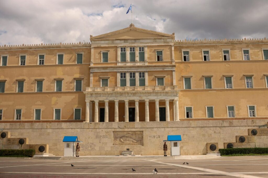 Front view of the historic Greek Parliament building in Athens with the national flag flying above.