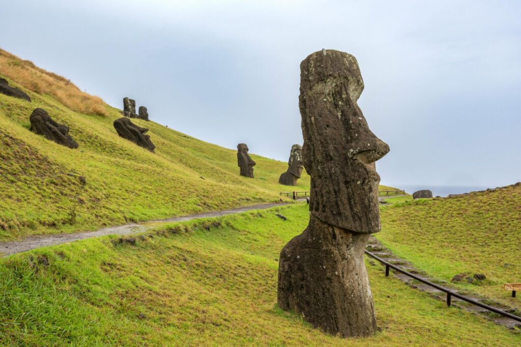 Ancient Moai statues dot the verdant landscape of Easter Island, standing majestically on a hillside.