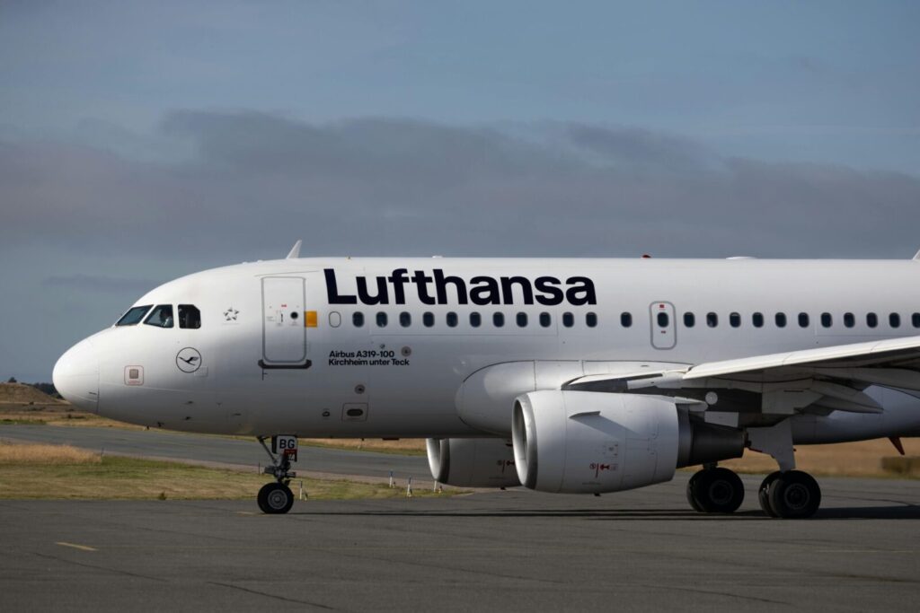 Lufthansa Airbus A319 aircraft at airport runway under clear sky, ready for takeoff.