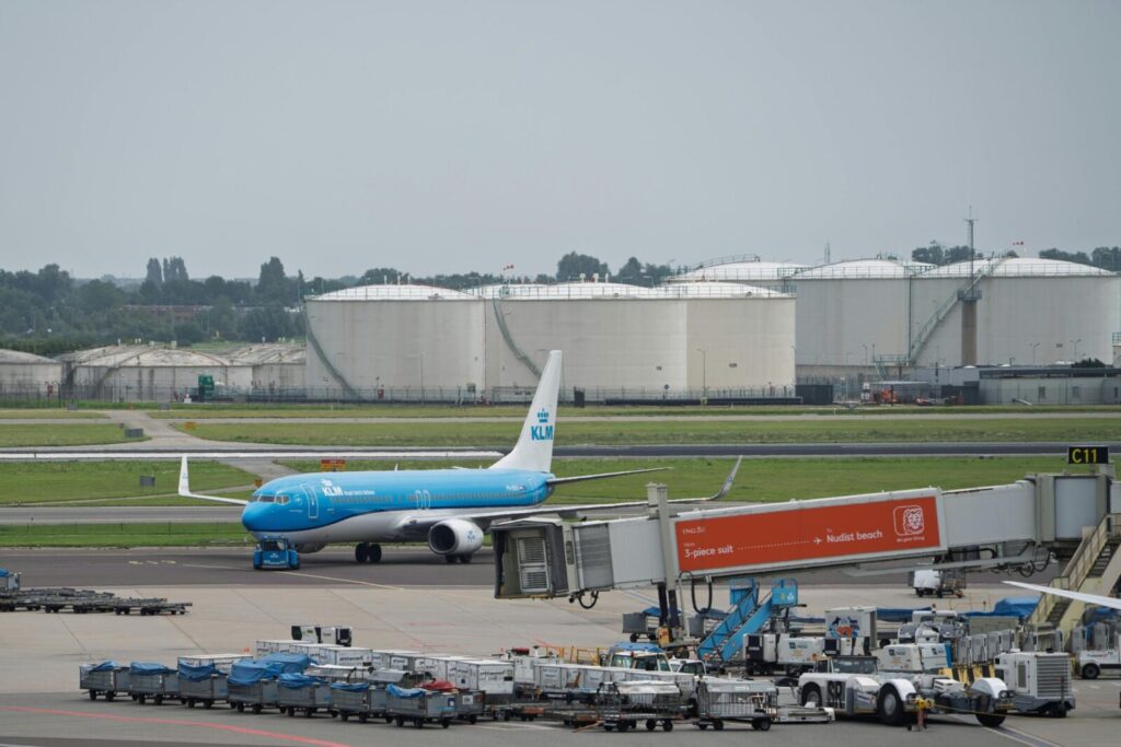 A KLM airplane is positioned on the runway of an airport, ready for takeoff.