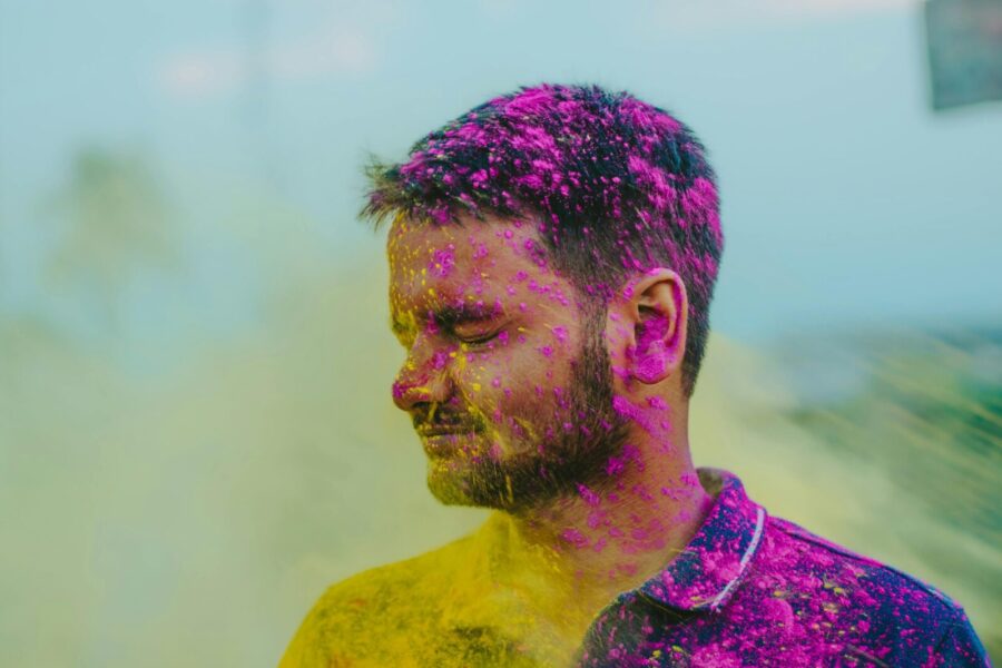 Vibrant portrait of a man covered in colorful powders celebrating Holi outdoors.