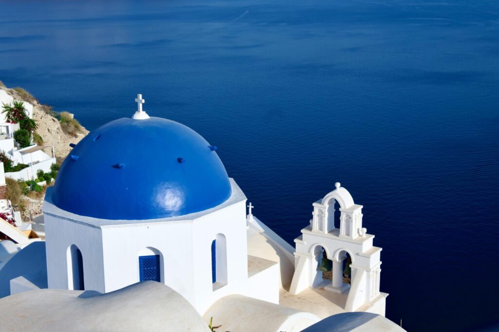 Breathtaking view of Santorini's blue-domed church overlooking the Aegean Sea, capturing Greek architecture.