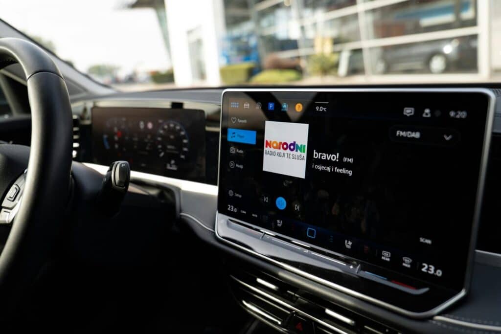 Inside view of a car with a sleek digital dashboard showing navigation and media controls.