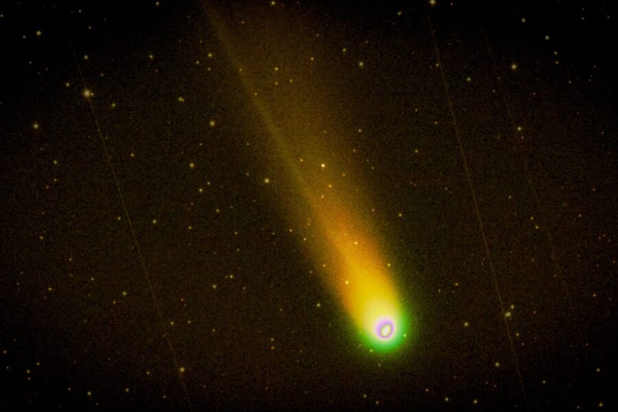 Colorful comet with glowing trail streaking across a starry night sky.