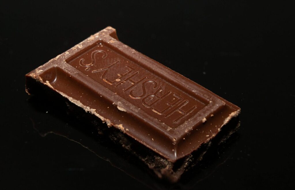 Macro shot of a Hershey's chocolate piece on a shiny black background.