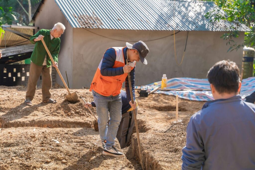 Adults and a senior working together on a construction project outdoors.