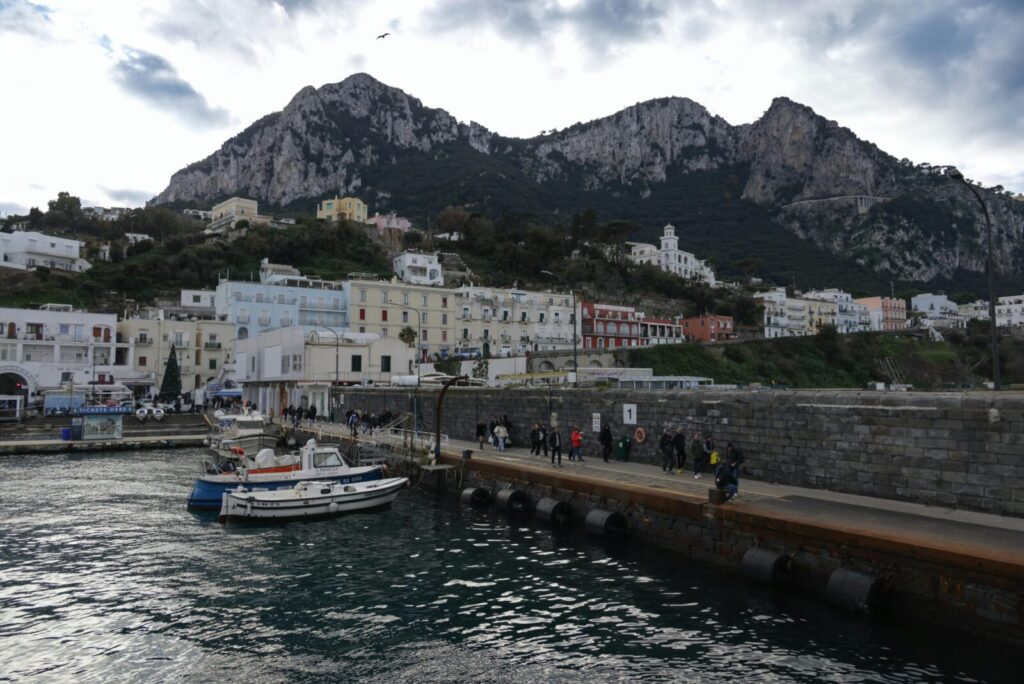 A stunning view of the port of Capri with Mediterranean architecture and scenic mountains.