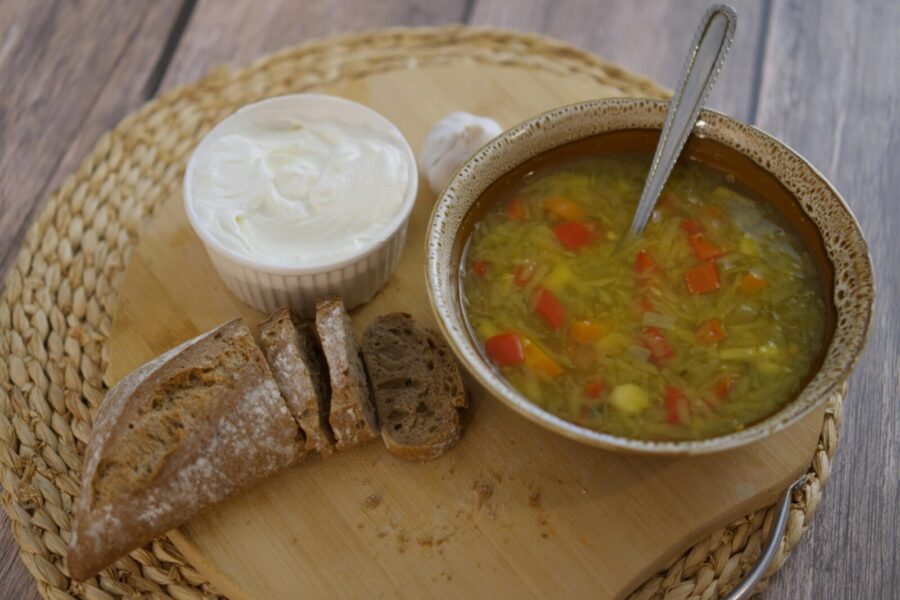 A cozy rustic lunch featuring vegetable soup with crusty bread and creamy spread.