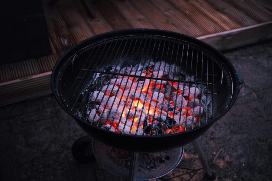 Close-up of glowing charcoal briquettes in a round outdoor grill, ready for barbecue cooking.