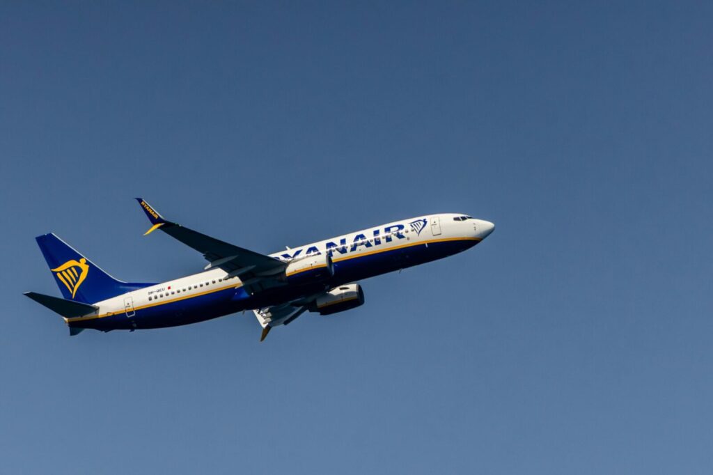 Ryanair airplane flying high against a clear blue sky in Cinisi, Sicily, Italy.