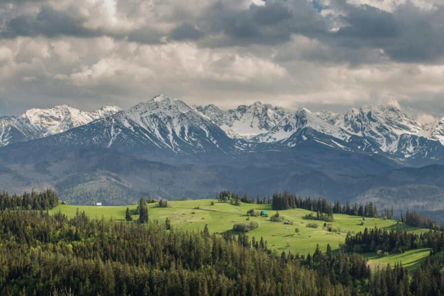 Scenic landscape of the Tatra Mountains with lush greenery and dramatic clouds.
