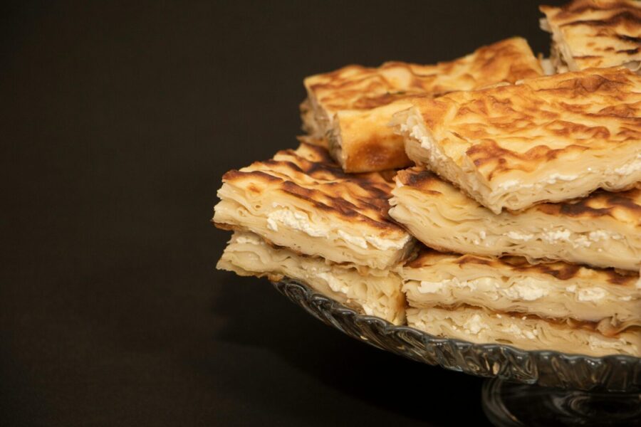 Close-up shot of traditional flaky pastry pie slices stacked on a glass plate.