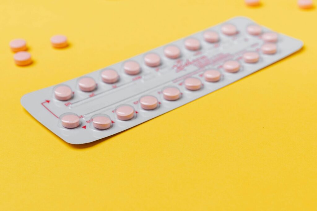 A blister pack of pink pills placed on a vibrant yellow background, symbolizing medicine and healthcare.