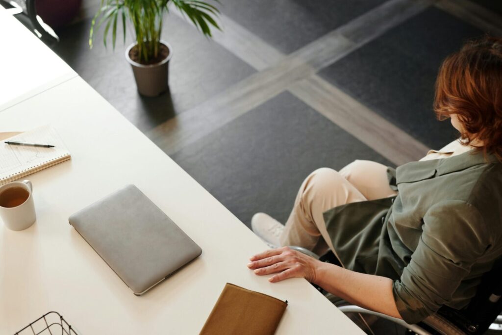 A woman working at a desk with a laptop and coffee in a modern office space.