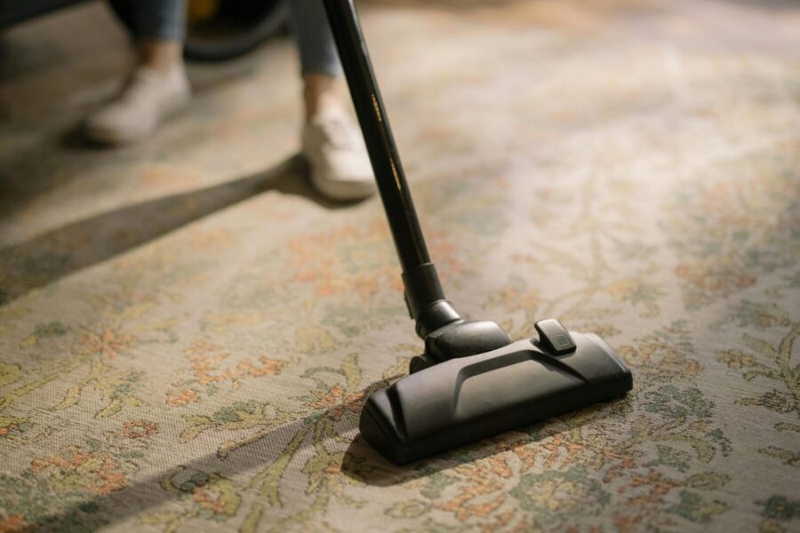 Close-up of a vacuum cleaner on a patterned carpet in a sunlit room, capturing a moment of household cleaning.