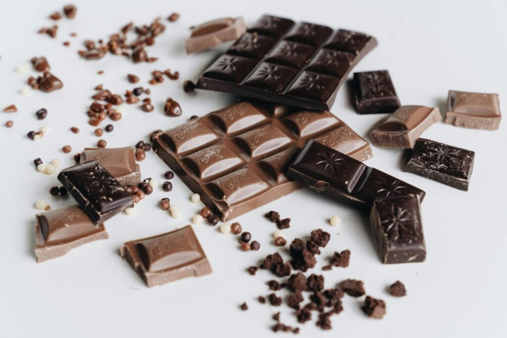 A delicious assortment of milk and dark chocolate bars with cocoa nibs on a white background.