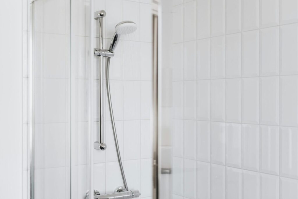 Stylish shower setup with chrome fixtures and clean white tiles.